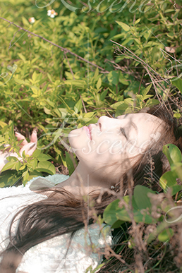 草むらに寝転がり深呼吸する女性
