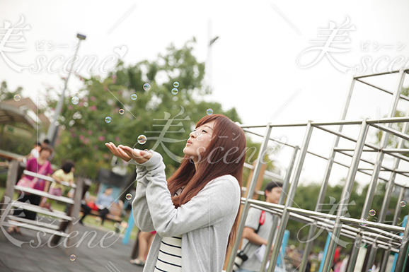 公園に漂うシャボン玉で遊ぶ女性