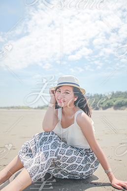 青空の下ビーチに座り笑う女性