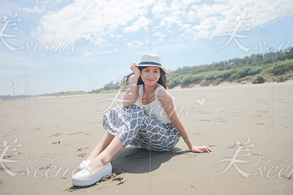浜辺で休憩するハットの似合う女性