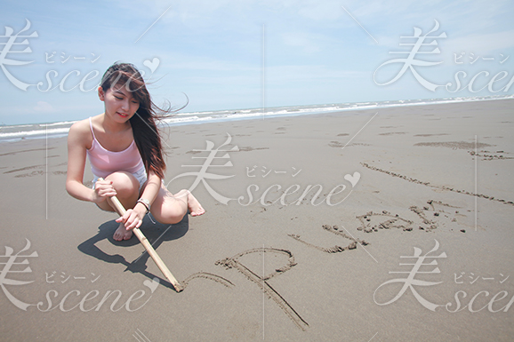 砂浜に自分の名前を書く女性