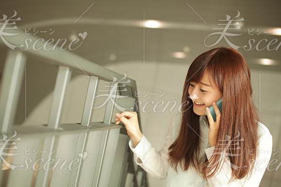 スマホで電話しながら、笑顔で階段を上る女性