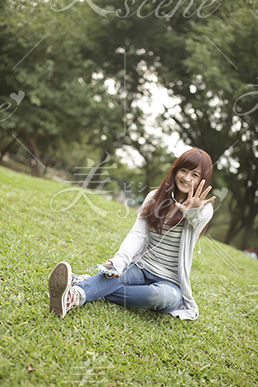 芝生に座りスマホで音楽を聴く女性12