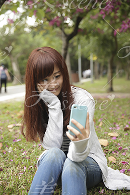 芝生の上に座り笑顔で自撮りをする女性