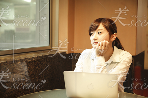 喫茶店でパソコンを打ちながら窓の外を見る女性2