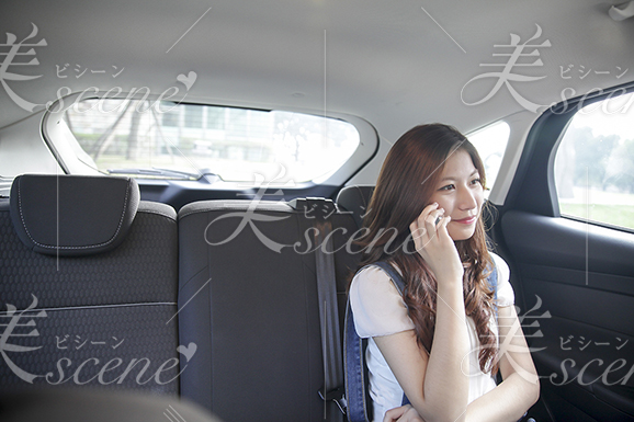 ドライブ中後部座席で電話をする女性
