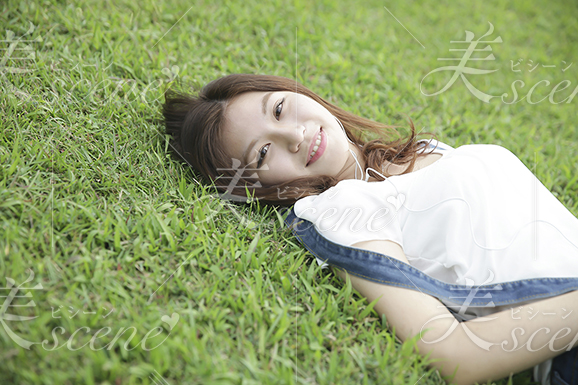 芝生に寝そべって微笑む女性