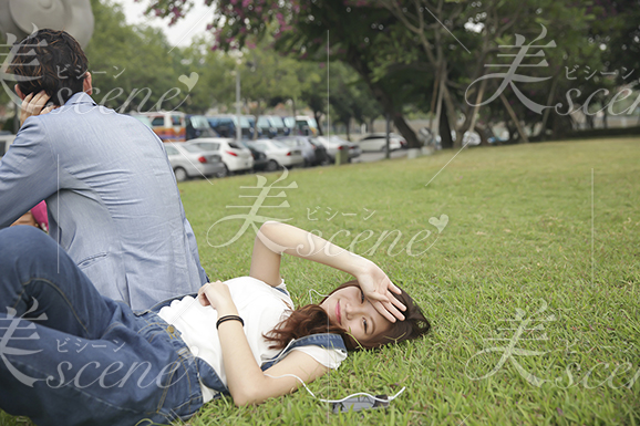 彼氏の横で芝生に寝そべる女性 美人女性モデルの写真素材なら美scene