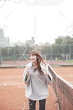 笑顔でテニスコートを走る女性