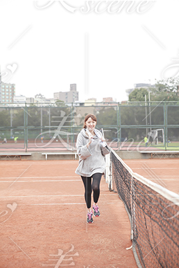 笑顔でテニスコートを走るポニーテールの女性