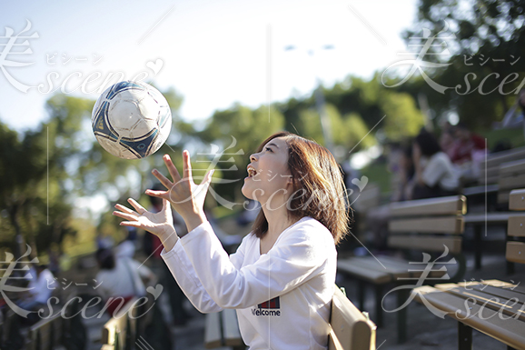 ベンチでサッカーボールを上に投げる女性