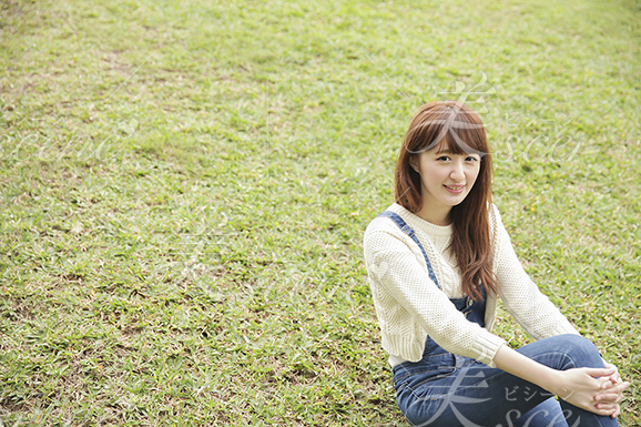 芝生の上に座り膝を抱え微笑む女性