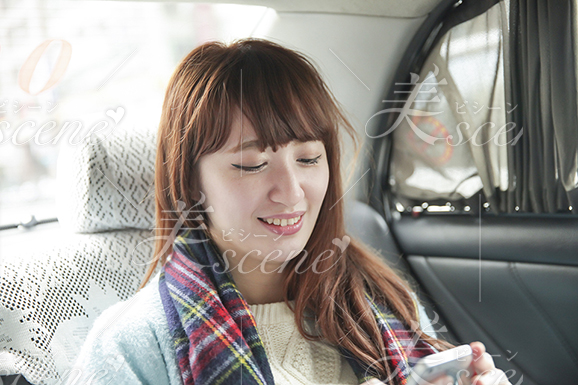 タクシーに乗り笑顔でメールを打つ女性