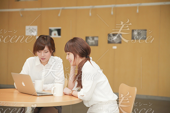 カフェでノートパソコンを開き、談笑する女性二人