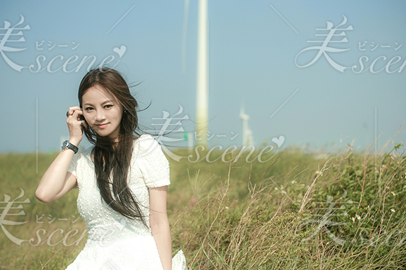 草原で風に吹かれ、髪を耳にかける女性