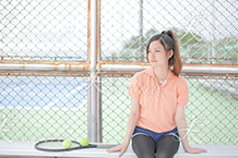 テニスコートで遠くを見つめる女性