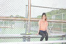 テニスコーチのベンチで友達を待つ女性