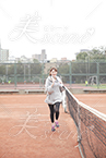 笑顔でテニスコートを走るポニーテールの女性