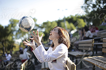 ベンチでサッカーボールを上に投げる女性