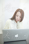 ノートパソコンを見つめるロングヘアーの女性