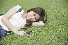 芝生の上で寝転ぶ・座る・音楽を聴く女性
